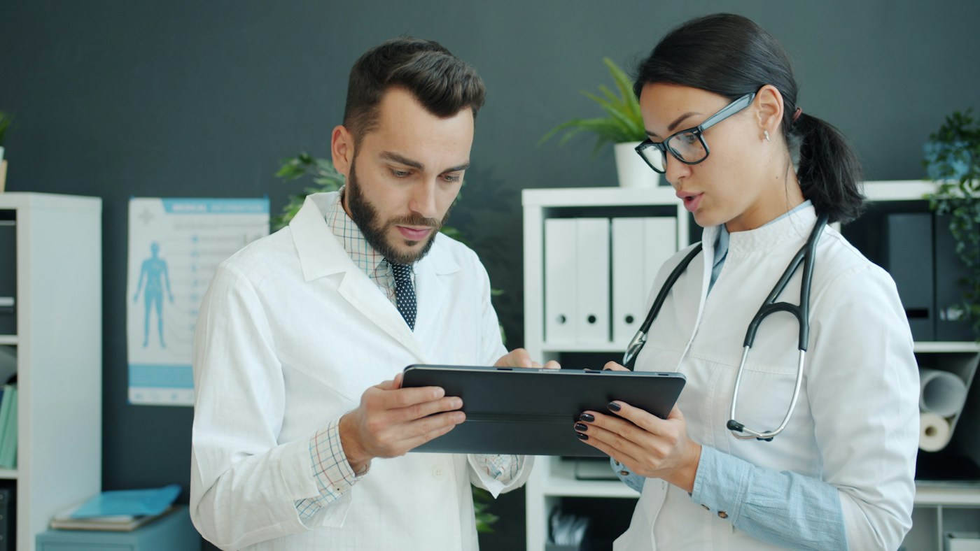 Illustrative photograph: Two medical professionals reviewing a digital tablet